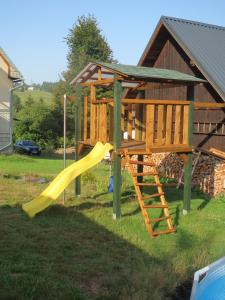 a playground with a yellow slide in a yard at Wellness apartmán TERASA in Bozkovska