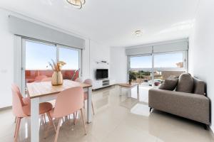 a dining room and living room with a table and chairs at Aparthotel Laguna Rosa in Los Montesinos