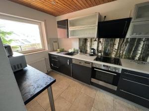 a kitchen with black cabinets and a sink and a window at Ferienhaus Samy - Feldberg in Feldberg