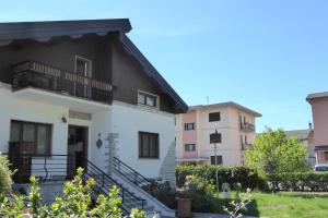 a white house with a balcony and a building at House Angy in Ponte nellʼAlpi