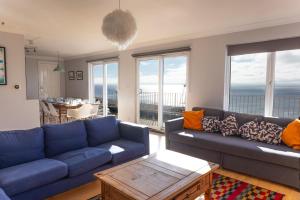 a living room with a blue couch and a table at Pier Court Apartments Brighton in Brighton & Hove