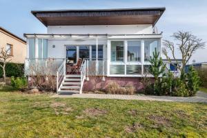 a small white house with a chair on the front porch at Ferienhaus am See mit Boot in Mustin