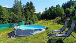 a hot tub and two chairs in a grassy field at Wellness apartmán TERASA in Bozkovska