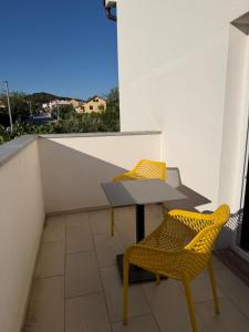 two yellow chairs and a table on a balcony at Muring Apartments in Tribunj