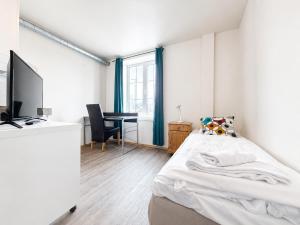 a bedroom with a bed and a desk with a television at Hotel Toranes in Mo i Rana