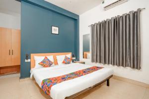 a bedroom with a large bed and a blue wall at Fabhotel Namaskar - Nr Udayagiri and Khandagiri caves in Bhubaneshwar