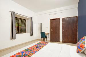 a bedroom with a bed and a chair and a window at Fabhotel Namaskar - Nr Udayagiri and Khandagiri caves in Bhubaneshwar +25 photos