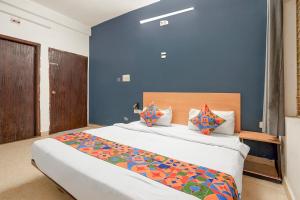 a bedroom with a large bed with a blue wall at Fabhotel Namaskar - Nr Udayagiri and Khandagiri caves in Bhubaneshwar