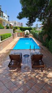 a swimming pool with two chairs and a table next to it at Anavyssos Riviera Cozy Bee Home Maisonette in Anavyssos