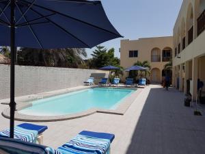a swimming pool with chairs and an umbrella at Dandimayo Hotel Bar & Restaurant in Serekunda