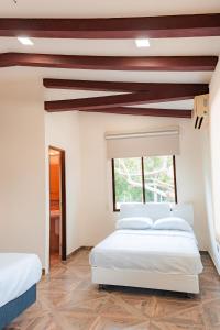 a bedroom with two white beds and a window at Finca La Macarena, Playas Villamil in Playas +15 photos