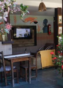 a living room with a table and a tv on a wall at Hospedagem La Bilbaina in Porto Seguro