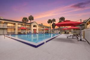 a pool at a resort with red umbrellas at Disney Studio 2 Queens & Shuttle in Kissimmee