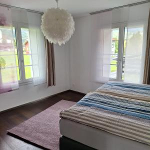 ein Schlafzimmer mit Bett, Fenstern und Kronleuchter in der Unterkunft Sandras Flat in Giswil