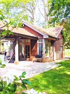 a log cabin with a porch and a patio at Rural Cottage Retreat, Near Goodwood Festival of Speed, Dog Friendly with Shared Outdoor Pool, gardens & Tennis, Free Parking! Chichester Holiday Properties in North Mundham