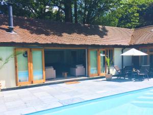 a house with glass windows and a swimming pool at Rural Cottage Retreat, Near Goodwood Festival of Speed, Dog Friendly with Shared Outdoor Pool, gardens & Tennis, Free Parking! Chichester Holiday Properties in North Mundham