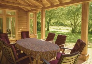 a screened in porch with a table and chairs at Rural Cottage Retreat, Near Goodwood Festival of Speed, Dog Friendly with Shared Outdoor Pool, gardens & Tennis, Free Parking! Chichester Holiday Properties in North Mundham