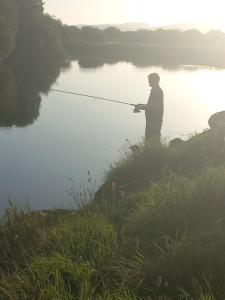 a man standing in the water holding a fishing rod at Fishing in Foxford