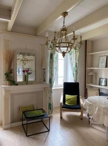 a dining room with a chandelier and a table and a chair at Appartement cosy - au cœur du bourg in Crozon