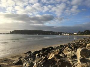 a beach with rocks and the ocean on a cloudy day at Appartement cosy - au cœur du bourg in Crozon