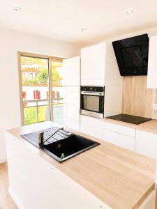 a white kitchen with a sink and a microwave at Cosy Flat Cannes in Le Cannet