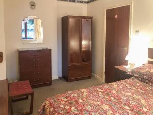 a bedroom with a bed and a dresser and a cabinet at Forge Mill Cottage in Dalbeattie +10 photos