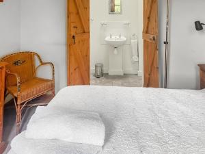 a bedroom with a bed and a sink and a chair at Stocks Tree Cottage in Preston Wynne