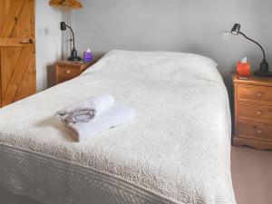 a bed with a white blanket and a towel on it at Stocks Tree Cottage in Preston Wynne