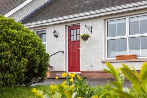 a red door on a house with a yard at Coolbuck Cottage in Lisbellaw