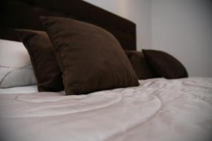 Una cama blanca con almohadas marrones. en Sarajevo Luxury Apartments, en Sarajevo