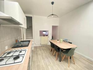 a kitchen with a stove and a table with chairs at L'Apart Amiens in Le Treuil +1 photo