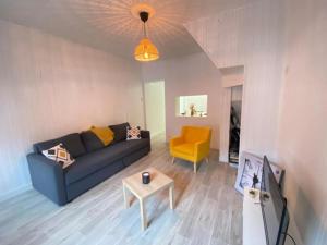 a living room with a blue couch and a yellow chair at L'Apart Amiens in Le Treuil