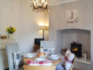 a dining room with a table and chairs and a fireplace at Sonny Cottage in Glanamman