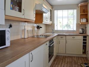 a kitchen with white cabinets and a wooden counter top at Sonny Cottage in Glanamman