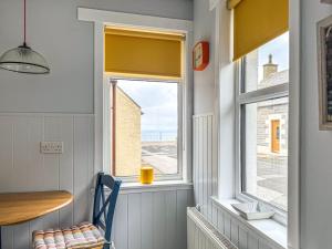 a room with a window with a chair and a table at Three Creeks Cottage in Portknockie +11 photos