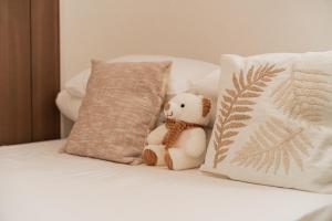 a teddy bear sitting next to a pillow on a bed at Poka Premium Kuramae Luxury 2BR Suite Brand-New in Tokyo