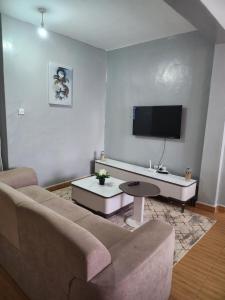a living room with a couch and a flat screen tv at Zariah Homes 1 in Kakamega