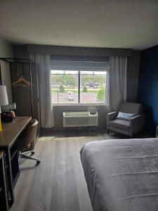 a bedroom with a bed and a desk and a window at Rodeway Inn in Portage
