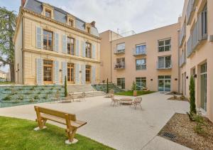 a courtyard with benches and tables in front of a building at Résidence de Bergerac in Bergerac
