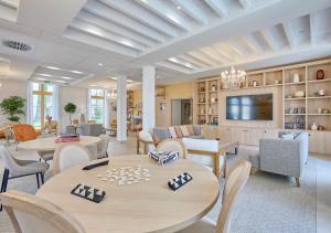 a living room with tables and chairs and a tv at Résidence de Bergerac in Bergerac