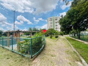 a fence in a park with a building in the background at Apartamento de 3 quartos, climatizado com lazer completo in Brasília
