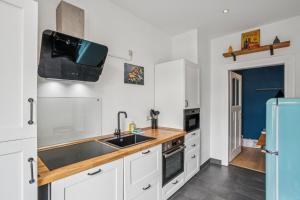a kitchen with white cabinets and a sink and a refrigerator at Arbio I Modern Apart near Leipzig Stötteritz in Leipzig