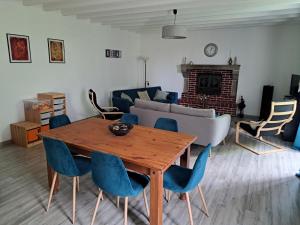 a living room with a wooden table and blue chairs at Le Cottage de Paul et Angéline in Boismé