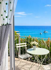 a table and chairs on a balcony with the ocean at Kalimera Aegina in Agia Marina Aegina