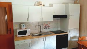 a kitchen with white cabinets and a sink and a microwave at Apartments Krn in Drežniške Ravne