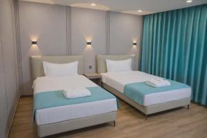 two beds in a hotel room with blue curtains at Khiimori Hotel in Ulaanbaatar