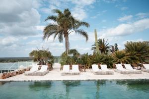a pool with white lounge chairs and palm trees at Finca Hotel Rural Es Turó Spa in Ses Salines