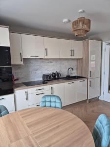 a kitchen with white cabinets and a table with chairs at The Ledger Rooms in Gort