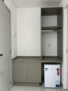 a white kitchen with a refrigerator and a shelf at Areiao Park Hotel in Goiânia