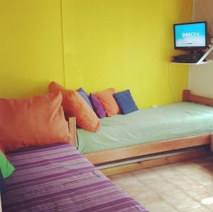 a room with two beds and a tv on a wall at La Blau in Mendoza